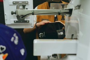 man using embroidery machine to customise apparel
